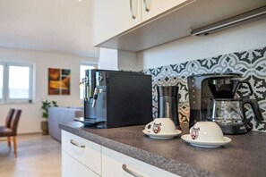 A modern kitchen with a coffee maker, a refrigerator, and a patterned backsplash. - Black Forest jewel terrace flair (Bonndorf im Schwarzwald)