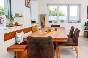 A dining area with a wooden table, cushioned chairs, and a bench. - Black Forest jewel terrace flair (Bonndorf im Schwarzwald)