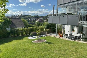 A modern house with a glass balcony, a well-maintained lawn, and a view of a village. - Black Forest jewel terrace flair (Bonndorf im Schwarzwald)