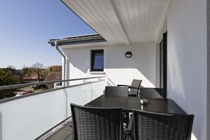 Ein Balkon mit Tisch und Stühlen, einem kleinen Fenster und einem Geländer.