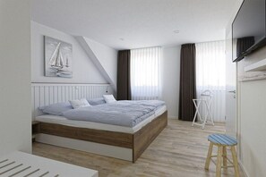 A modern bedroom with a bed, a painting, a window with curtains, and a small stool. - Holiday apartment with 1 bedroom (Cuxhaven)