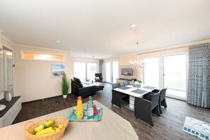 Ein modernes Wohnzimmer mit Essbereich, einer Couch, einem Couchtisch und einer Kandelaber.
