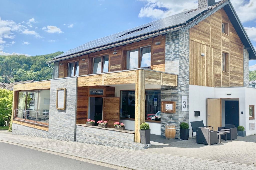 A modern building with a wooden facade, large windows, and outdoor seating.