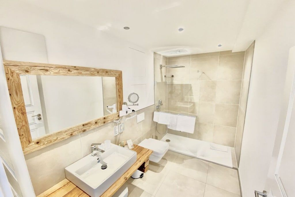 A modern bathroom with a wooden vanity, a large mirror, a bathtub, and a glass-enclosed shower.