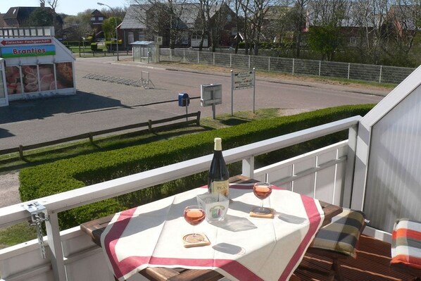Ein Balkon mit einem Tisch für zwei Personen, einer Weinflasche und Gläsern.
