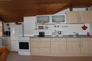 A compact kitchen with a microwave, toaster, kettle, and a sink. - Holiday apartment with 2 bedrooms (Roßhaupten)