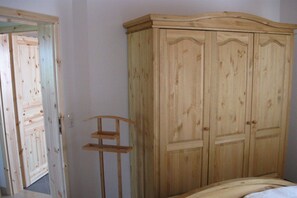 A bedroom with a wooden wardrobe, a bed, and a mirror. - Holiday home with 2 bedrooms (Greetsiel)