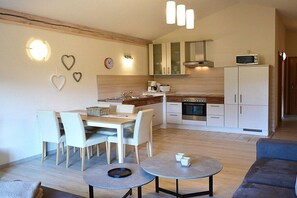 A compact living space with a dining area, kitchenette, and a sofa. - Holiday apartment with 2 bedrooms (Bodenmais)