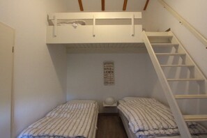 A small, compact room with two single beds, a white ladder, and a wall-mounted shelf. - Holiday home Deichblick E 16 (Butjadingen)