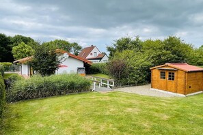 Ein Wohnhaus mit gepflegtem Rasen, einem Holzschuppen und einem Haus mit Satteldach.