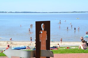 Ein Strand mit Schwimmern und einer großen Skulptur im Vordergrund.