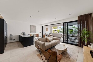 A modern living space with a sofa, chairs, a dining table, and a kitchen area. - The Bank | Poolside Apt. | 5m to Mambo & Jan Thiel (Willemstad)