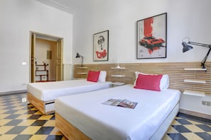 Ein Hotelzimmer mit zwei Betten, einem Schachbrettmuster-Boden und Bildern an den Wänden.