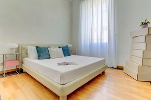 A bedroom with a bed, bedside tables, a window with curtains, and a stack of boxes. - Vatican City View | 2 Bedrooms & 2 Bathrooms (ROMA)