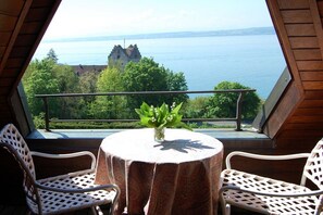 A balcony with a table and chairs, overlooking a body of water and a castle. - Family Dr. Wolfgang Trautwein (Meersburg)