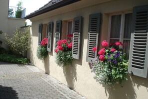 A building with multiple windows, each with shutters, and flower boxes with various flowers. - Family Dr. Wolfgang Trautwein (Meersburg)