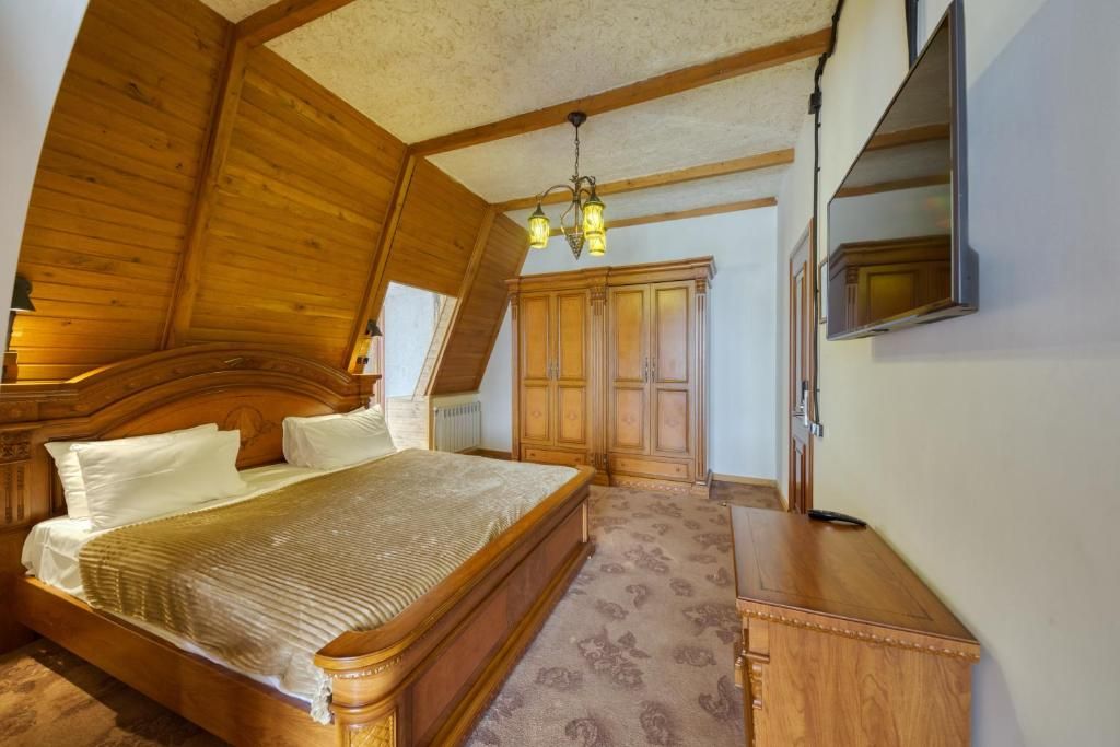 Un dormitorio con cama de madera, armario y televisor montado en la pared.