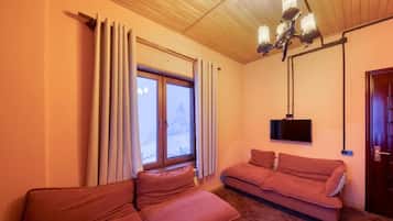 A room with two sofas, a television, and a window with curtains.