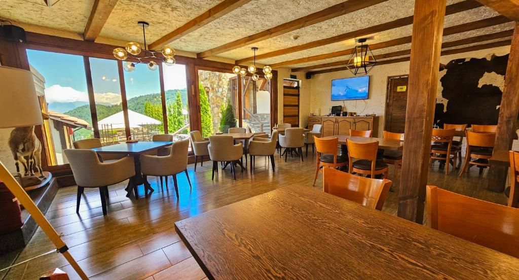 A dining area with multiple tables and chairs, a television mounted on the wall, and a view of the outdoors.