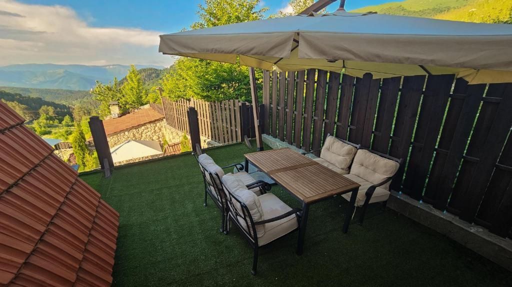 Une terrasse avec une table et des chaises, une clôture en bois et une vue sur le paysage.
