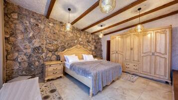 A bedroom with a stone wall, wooden bed frame, and a large wardrobe.