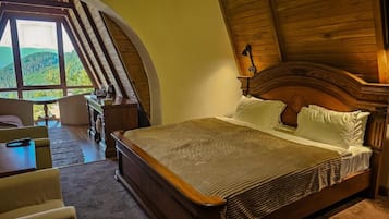 A bedroom with a large bed, a wooden headboard, a nightstand, a desk, and a chair.
