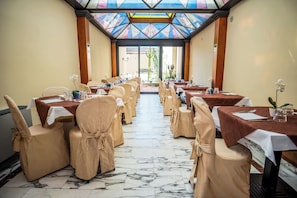 A conference room with tables and chairs, a tiled floor, and a glass ceiling. - Hotel Grande Bretagne (Montecatini Terme)