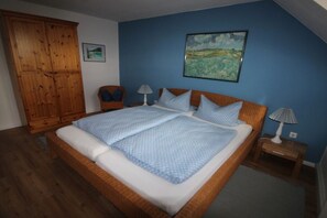 Ein Schlafzimmer mit einem großen Bett, einem Holzschrank, zwei Nachttischen und einem Bild an der Wand.