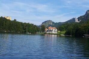 A lakeside property with a large building featuring multiple balconies, surrounded by lush greenery and hills. - 1 Country House Nina (Hohenschwangau)