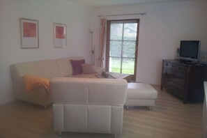 A living room with a sofa, a coffee table, a television, and a window with curtains. - 1 Country House Nina (Hohenschwangau)
