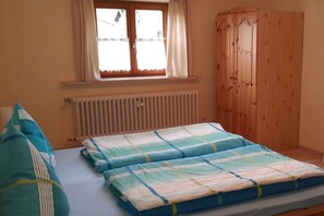A bedroom with a bed, a window with curtains, a radiator, and a wooden wardrobe. - 1 Country House Nina (Hohenschwangau)
