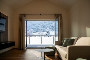 A living room with a sofa, a round table, and a large window with curtains. - Holiday apartment with 1 bedroom (Pfronten)