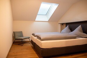 A bedroom with a skylight, a bed, a chair, and a wooden floor. - Holiday apartment with 1 bedroom (Pfronten)