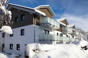 A multi-story hotel with balconies, snow-covered surroundings, and a mountainous backdrop. - Holiday apartment with 1 bedroom (Pfronten)