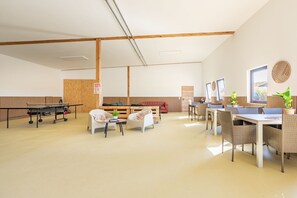 Une pièce spacieuse équipée d’une table de ping-pong, d’un coin salon et offrant une vue sur l’extérieur.