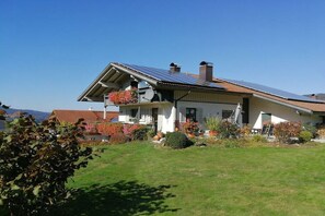 A two-story house with a sloped roof, solar panels, and a well-maintained garden. - Holiday apartment in Bodenmais with sauna (Bodenmais)