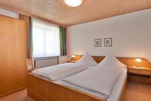 A double bed with two bedside tables, a wooden wardrobe, and a window with curtains. - Holiday apartment in Bodenmais with sauna (Bodenmais)