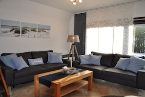 A modern living room with a sofa set, a coffee table, and a lamp. - Holiday home Seemuschel (Cuxhaven Duhnen)