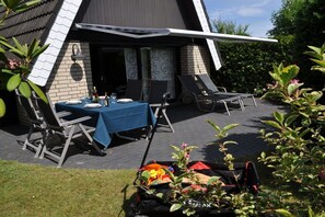 An outdoor dining area with a table set for two, chairs, and a covered seating area. - Holiday home Seemuschel (Cuxhaven Duhnen)