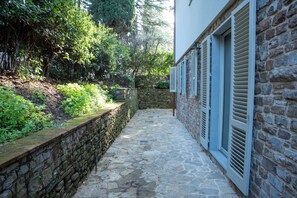 A stone pathway leading to a building with a stone wall and a wooden door. - BELLOSGUARDO HILL APARTMENT, FLORENCE (Toscana)