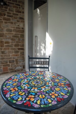 A round table with a colorful mosaic pattern, a chair, and a stone wall in the background. - BELLOSGUARDO HILL APARTMENT, FLORENCE (Toscana)