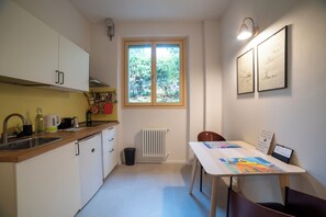 A compact kitchen with white cabinets, a window with a view of greenery, and a dining area with a table and chairs. - BELLOSGUARDO HILL APARTMENT, FLORENCE (Toscana)