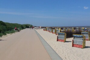 A beach walkway with sand on one side and a paved path on the other, lined with beach huts numbered 409. - Residence Albatros (Apt. 16) (Cuxhaven-Döse)