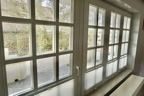 A room with large windows, a white radiator, and a white bench. - Lindenhof Holiday Apartment No. 2 (Wenningstedt-Braderup)