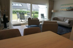 A hotel room with a sofa, chairs, a table, and a view of the outside. - House Carola Apartment 15 (Wenningstedt-Braderup)