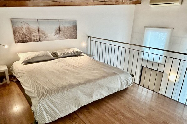 Une chambre à coucher avec un lit, une table de chevet, une rambarde et une fenêtre.