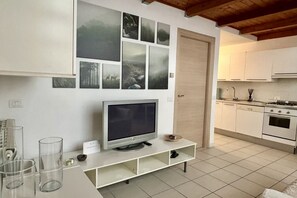 Une cuisine moderne avec des armoires blanches, un four encastré et un coin repas comprenant une table et des chaises blanches.