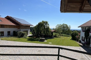 Ein Wohnhaus mit einem gepflasterten Innenhof, einer Solaranlage auf dem Dach und einem großen Baum.