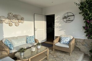 A sunlit patio area with wicker furniture, a coffee table, and decorative wall art. - Holiday home with 2 bedrooms (Cala Llombards)