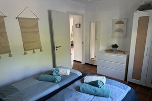A hotel room with two beds, a wardrobe, and a small bathroom. - Holiday home with 2 bedrooms (Cala Llombards)